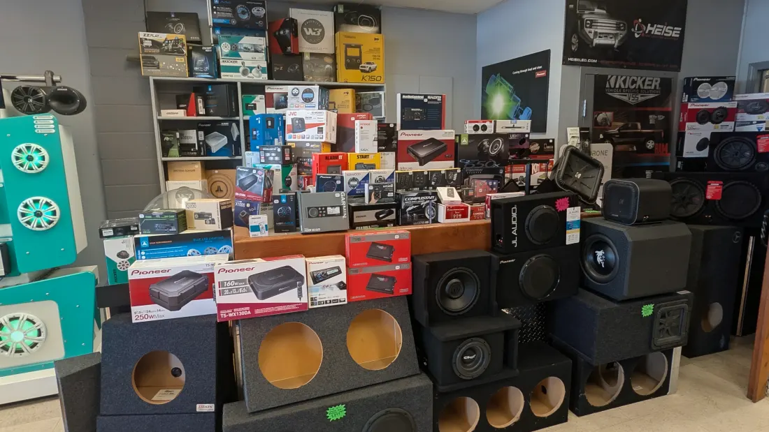 Wall of in-stock car audio gear — head units, amplifiers, speakers and subwoofer boxes at Traffic Jams Car Tunes & Toys