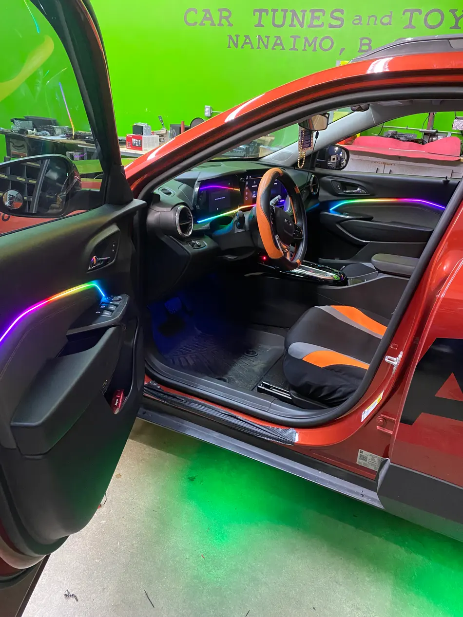 Multicolor RGBIC ambient lighting along the door sill, dash and steering wheel of a vehicle interior